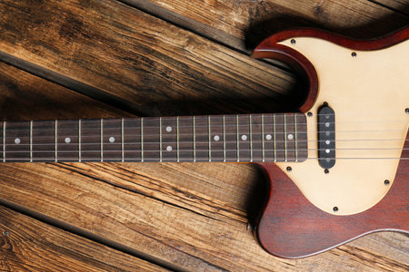Modern electric guitar on wooden background, top view. musical instruments