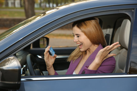 happy woman holding driving license in car