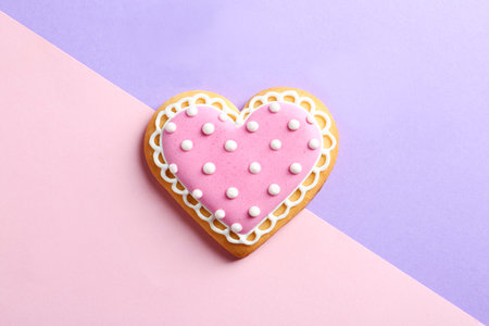 Decorated heart shaped cookie on color background, top view