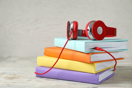 Modern headphones with hardcover books on wooden table. Space for textの写真素材