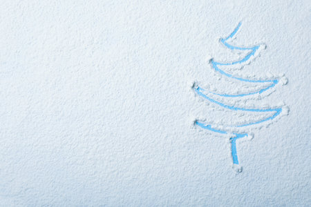 Christmas tree silhouette in snow on color background, top view with space for textの写真素材