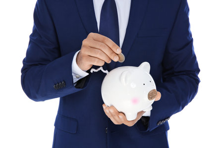 Young businessman putting money into piggy bank on white background, closeupの写真素材