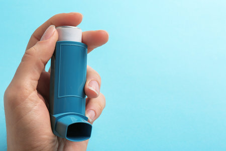 Woman holding asthma inhaler on color background. Space for textの写真素材