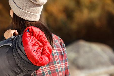 Female camper with sleeping bag outdoors, closeup. Space for text