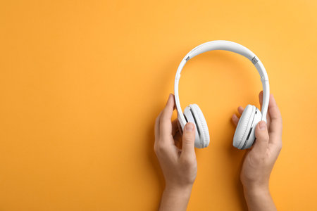 Woman holding headphones on color background, top view. Space for textの写真素材