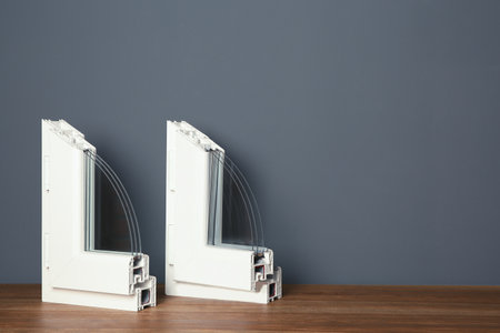 Samples of modern window profiles on table against gray wall, space for text. Installation service