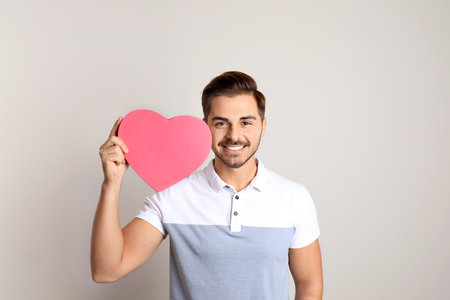 Portrait of young man with decorative heart on light backgroundの写真素材