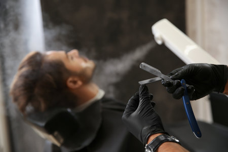 Hairdresser working with client at barbershop. Professional shaving serviceの写真素材