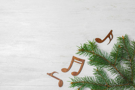 Flat lay composition with Christmas tree branch, music notes and space for text on white wooden backgroundの写真素材