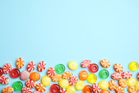 Flat lay composition with delicious colorful candies and space for text on color background