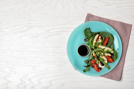 Plate with vegetable salad and balsamic vinegar on white wooden table, top view. Space for textの写真素材