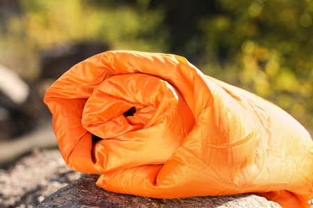Orange sleeping bag on rock outdoors. camping equipment