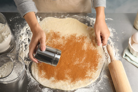 Woman making cinnamon rolls at table, closeup