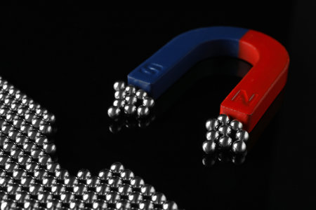 Magnet attracting chrome balls on black background. business leadership conceptの写真素材