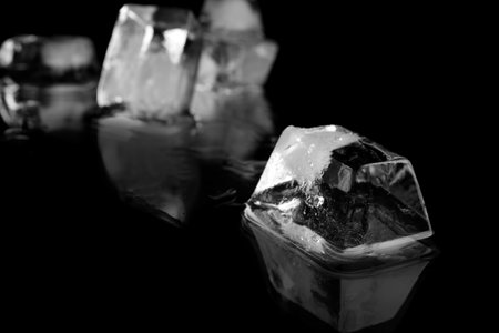 Ice cube on black mirror surface. Space for textの写真素材