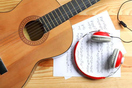 Beautiful classical guitar, headphones and music sheets on wooden background, top viewの写真素材