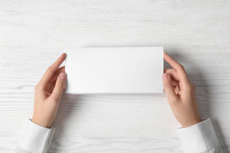 Woman holding blank brochure mock up on light background, top viewの写真素材