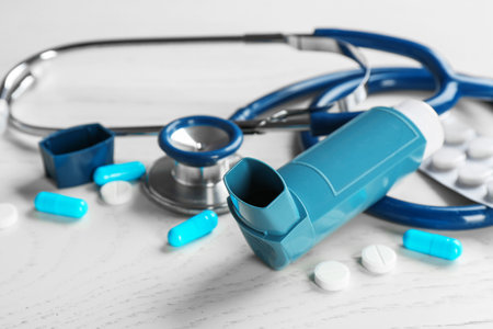 Asthma inhaler, stethoscope and pills on white wooden backgroundの写真素材