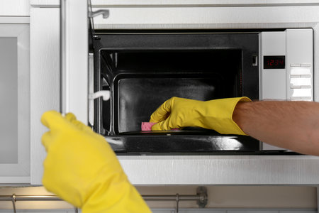 Man cleaning microwave oven in kitchen, closeupの写真素材