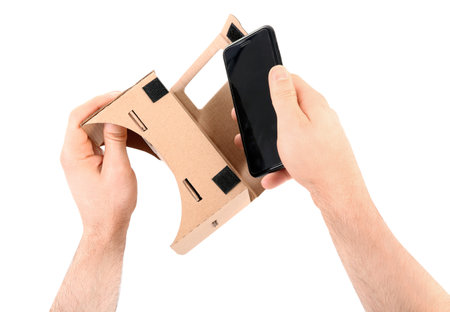 Man putting smartphone into cardboard virtual reality headset on white background, closeupの写真素材