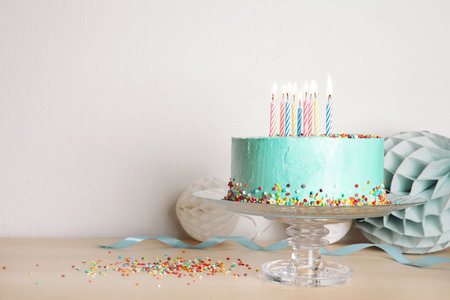 Stand with fresh delicious cake and birthday decorations on table. Space for textの写真素材