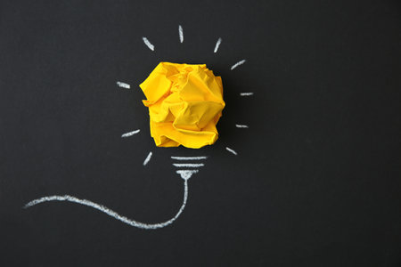 Composition with crumpled paper as lamp bulb and space for text on black backgroundの写真素材