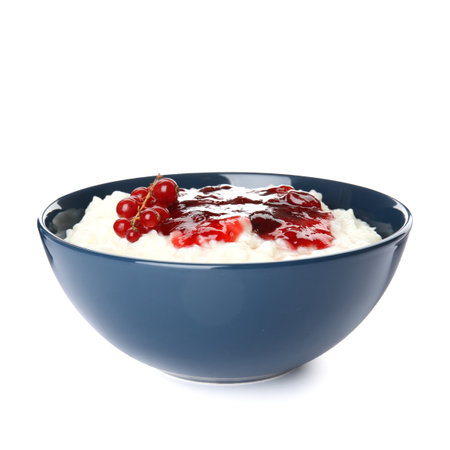Creamy rice pudding with red currant and jam in bowl on white backgroundの写真素材
