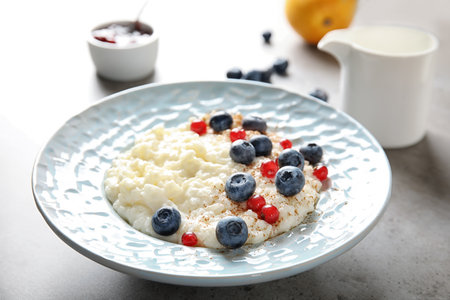 Creamy rice pudding with red currant and blueberries in bowl served on tableの写真素材