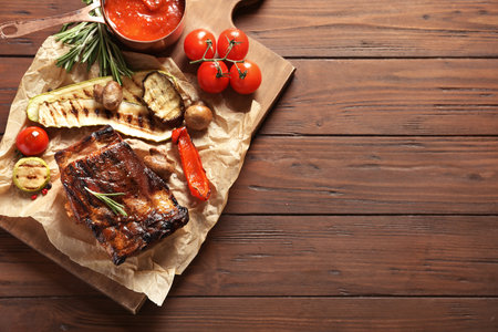 Flat lay composition with delicious barbecued meat on wooden background. Space for textの写真素材