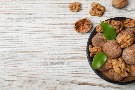 Plate with walnuts and space for text on wooden background, top viewの写真素材