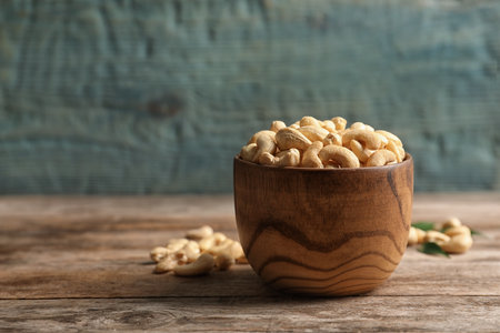 Tasty cashew nuts in bowl on wooden table. Space for textの写真素材