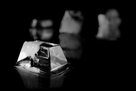 Ice cube on black mirror surface. Space for textの写真素材