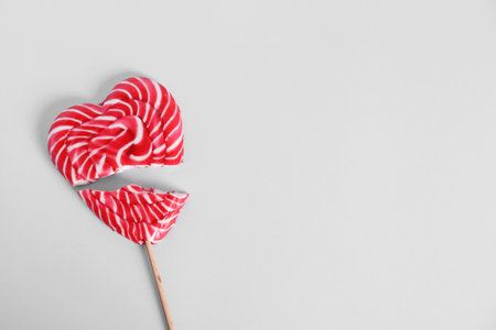 Broken heart shaped lollipop on white background, top view. Space for textの写真素材