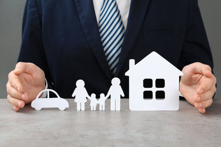 Man with cutout paper family, house and car at table, closeup. life insurance conceptの写真素材