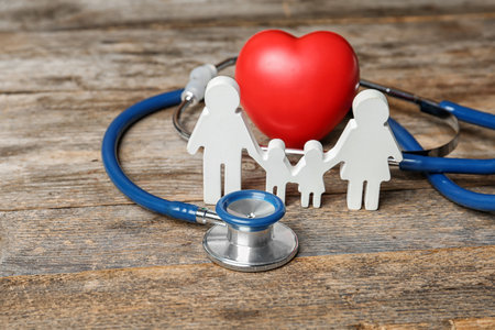 Family figure with stethoscope and heart on wooden background. life insurance conceptの写真素材