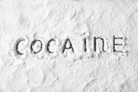 Word Cocaine written on white powder as background, top viewの写真素材