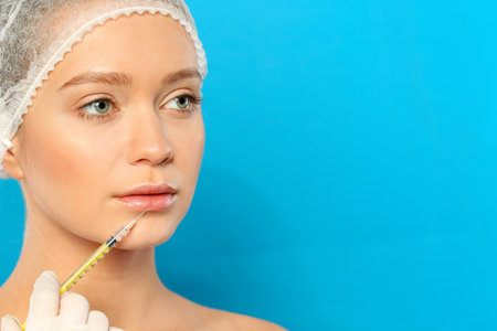 Young woman getting lips injection on color background, space for text. cosmetic surgery