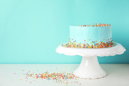 Fresh delicious birthday cake on stand against color background. Space for textの写真素材