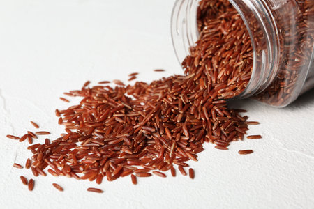 Pile of brown rice and jar on table, closeupの写真素材