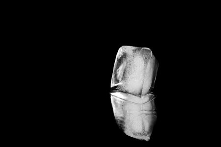 Ice cube on black mirror surface. Space for textの写真素材