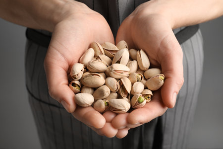 Woman holding organic pistachio nuts on gray background, closeupの写真素材