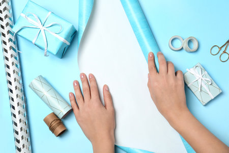 Woman decorating gift box on color background, top viewの写真素材