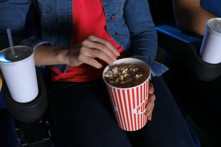 Young woman with popcorn watching movie in cinema, closeupの写真素材