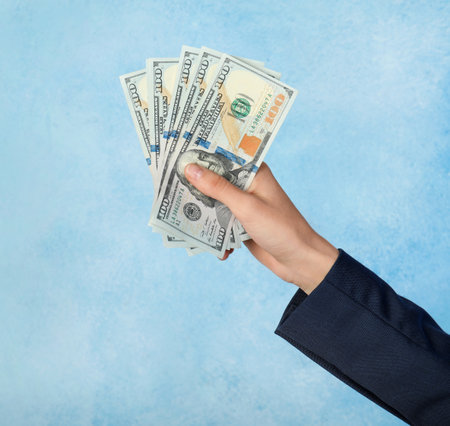 Woman holding bunch of dollar banknotes on color backgroundの写真素材