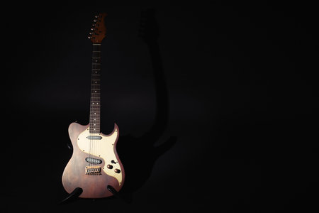 Electric guitar under spotlight on black background. Space for textの写真素材