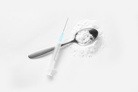 Spoon with cocaine and empty syringe on white background, top viewの写真素材