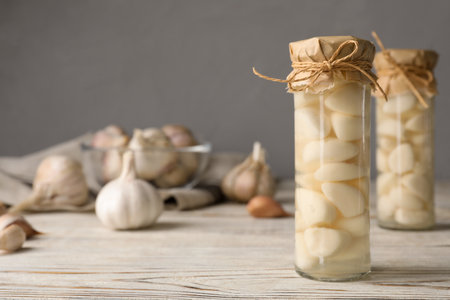 Preserved garlic in glass jar on wooden table. Space for textの写真素材
