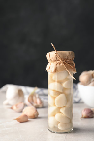 Preserved garlic in glass jar on table. Space for textの写真素材