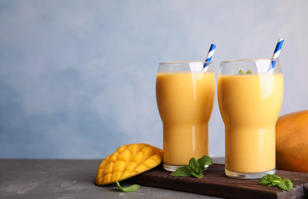 Glasses of fresh mango drink and fruits on table. Space for textの写真素材