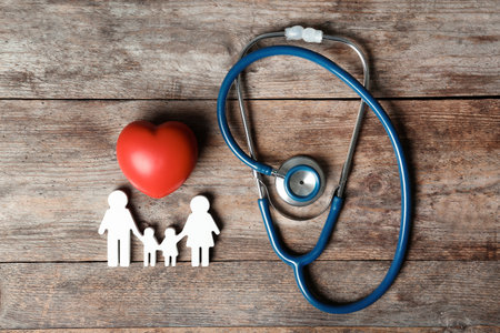 Flat lay composition with heart, stethoscope and family figure on wooden background. life insurance conceptの写真素材